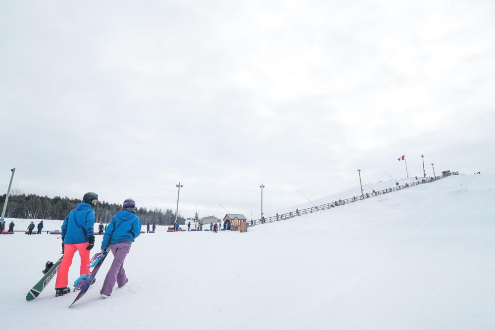 snowboarders at bottom of snowy hill