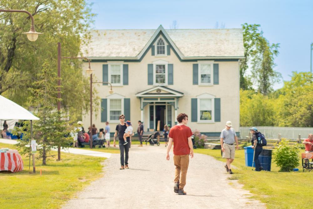 people standing outside historic home at village museum