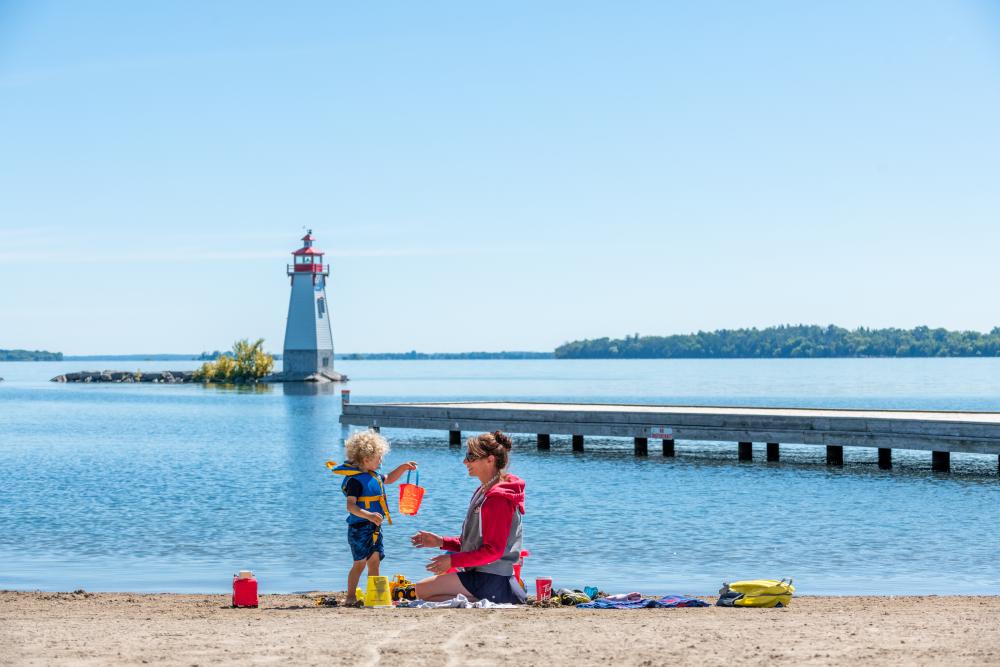 mother and child on beach with lighthouse in background