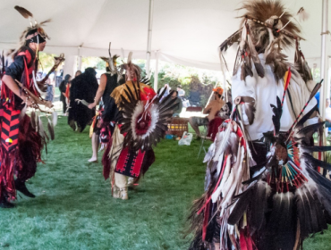 three men dressed in regalia dancing to drums