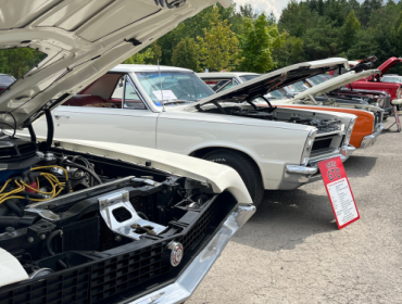 classic cars with the hoods up lined up in a line