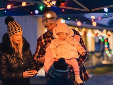 family standing under a lit tent at dusk 