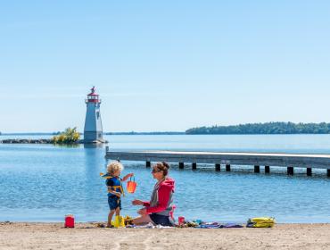 mother and child on beach with lighthouse in background