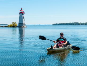 paddler on lake with lighthouse in background